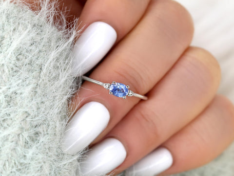 oval cornflower blue sapphire ring in trilogy style with two diamonds on white gold on middle finger