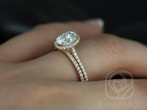 14kt gold bridal set with dainty oval moissanite halo engagement ring and matching diamond wedding band on finger