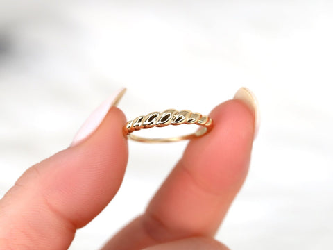 Petite 14kt gold croissant ring held between fingers