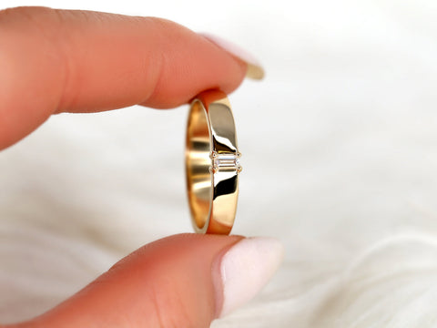 14kt gold baguette diamond wedding ring held between fingers