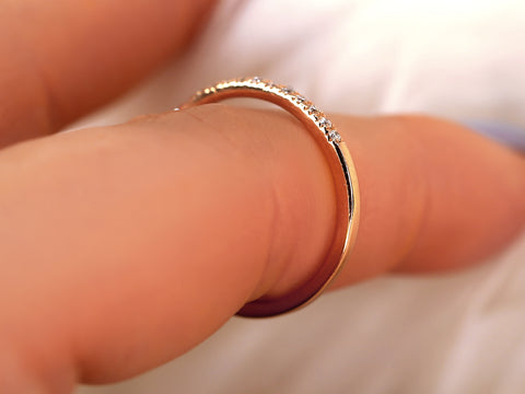 Gold ring with small diamonds on a finger against a blurred background