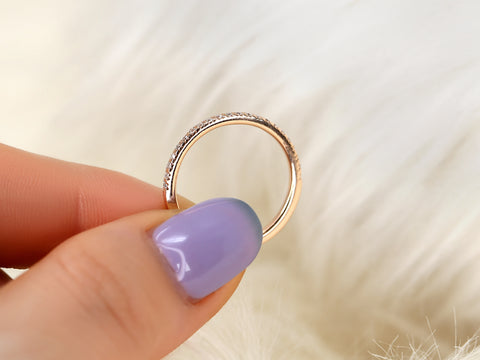 Gold ring held by a hand with purple nail polish on a soft white background