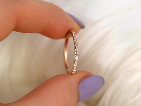 Rose gold ring with diamonds held by a hand with purple nail polish on a blurred background