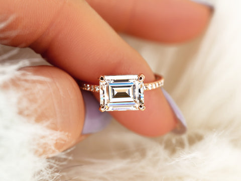 east west set emerald cut solitaire with diamonds on band on finger