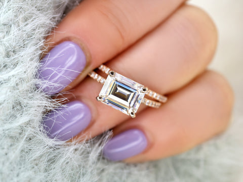 east west set emerald cut solitaire with diamonds on shank and matching diamond band on ring finger