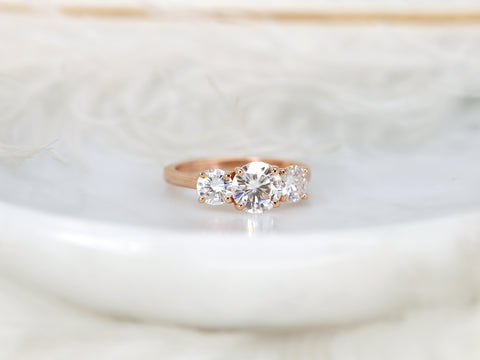 Rose gold ring with three moissanites on a soft white background