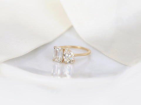 Elegant two-tone gold ring featuring emerald and pear-shaped moissanite stones on soft white surface