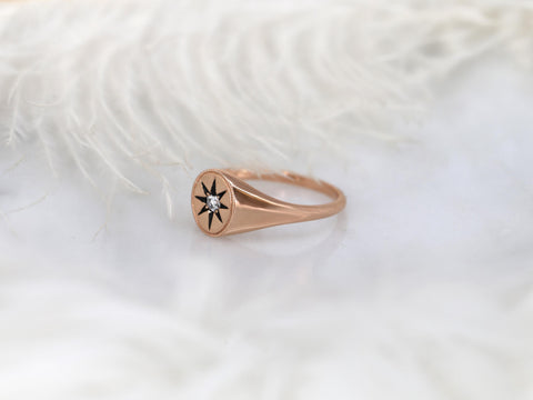 Rose gold 14kt ring with starburst design featuring a small center diamond on a soft white surface