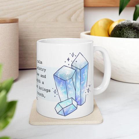 White ceramic mug featuring blue crystal illustrations and partial text on a kitchen countertop with fruit bowl nearby