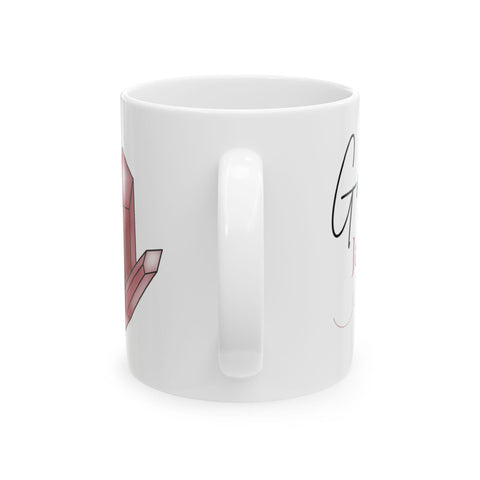White ceramic mug with soft pink crystal illustration and delicate script detail visible from handle side view