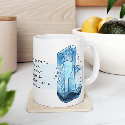 White ceramic mug with blue crystal birthstone design and partial inspirational text on a light countertop setting