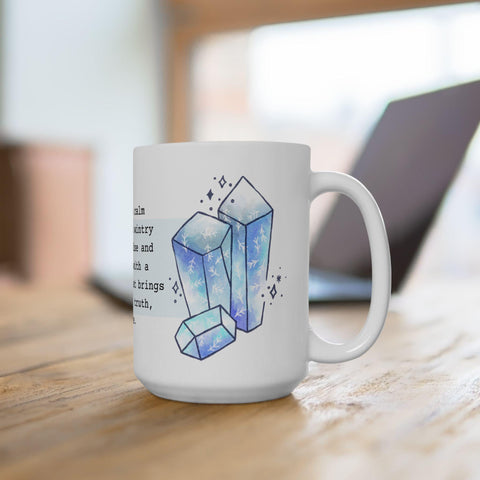 White ceramic mug with blue crystal artwork on wooden table in bright cozy workspace setting