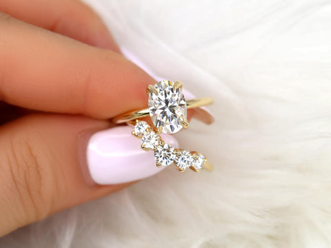 Close-up of hand holding two gold rings with sparkling moissanite stones on a soft white background