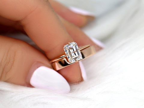 Close-up of a hand holding a 14kt gold solitaire ring with an emerald cut sparkling moissanite center stone