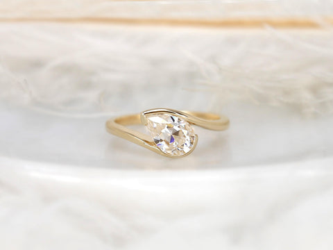 14kt gold ring with a tilted pear-shaped moissanite solitaire set on a delicate band against a soft background