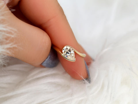 Delicate 14kt gold ring with a tilted pear-shaped moissanite solitaire, styled for engagement or fine jewelry gift