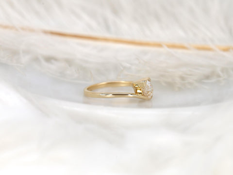 Delicate 14kt gold ring with tilted pear-shaped moissanite solitaire on a smooth band displayed on soft white feathers
