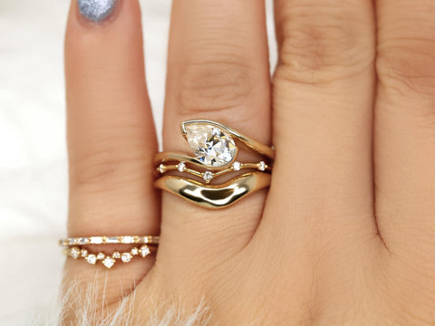 Elegant trio bridal set featuring a tilted pear-shaped moissanite solitaire with matching curved bands in 14kt gold