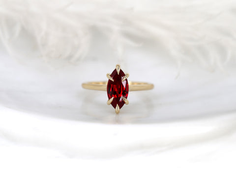 14kt gold ring showcasing a marquise-cut ruby solitaire with a minimalist elegant setting on a neutral background