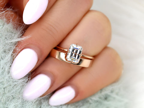 Close-up of hand with light pink nails wearing a 14kt gold bridal set featuring an emerald cut moissanite solitaire ring