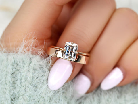 Emerald cut solitaire moissanite ring with matching 14kt gold band worn on hand with soft knit sleeve