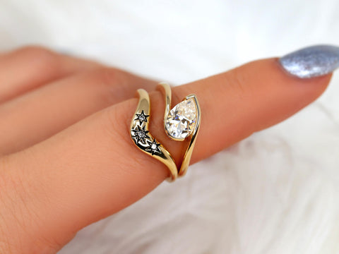 14kt gold moissanite ring with tilted pear-shaped stone and star-engraved curved band showcased on finger