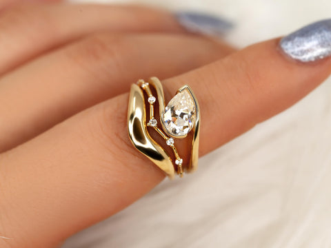 14kt gold bridal ring set with tilted pear moissanite and delicate diamond accents on finger close-up