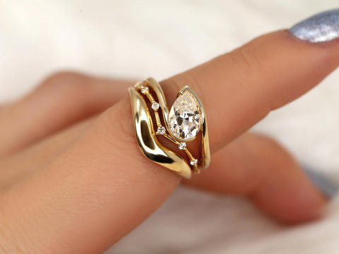14kt gold ring set with a tilted pear-shaped moissanite and accent stones, styled on a hand close-up