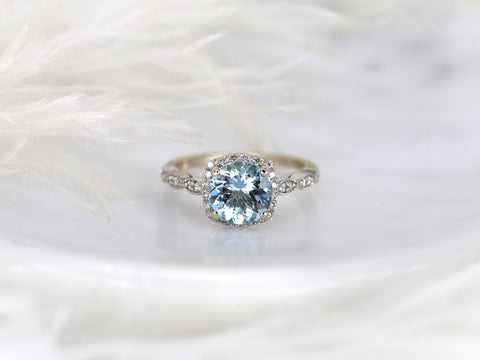Delicate 8mm aquamarine center stone with diamond halo and milgrain details on a fine gold band, elegant fine jewelry ring