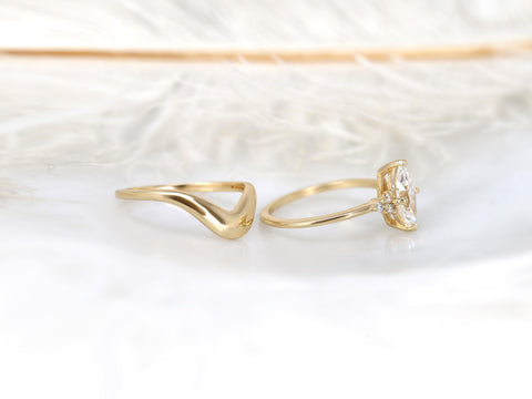 Delicate 14kt gold wedding band and moissanite marquise cluster engagement ring set on a soft white surface