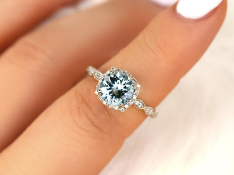 Close-up of an aquamarine ring with diamond halo and milgrain detailing on a delicate fine jewelry band.