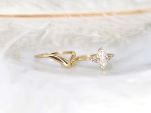 Elegant 14kt gold bridal set featuring a marquise moissanite engagement ring paired with a curved wedding band on soft fabric.