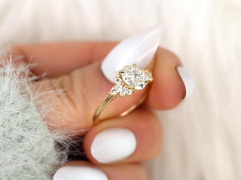 Gold ring with a diamond on a hand with white nail polish against a blurred background