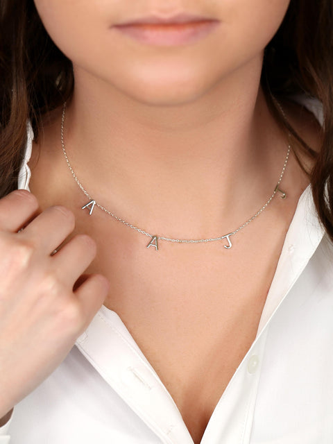 Person wearing a silver necklace with 'AJ' initials, close-up on neck and chest.