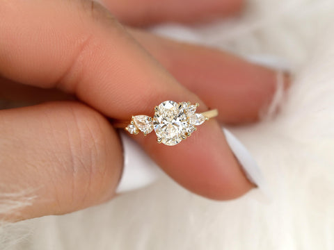 Gold ring with oval-shaped diamond on a finger against a blurred background