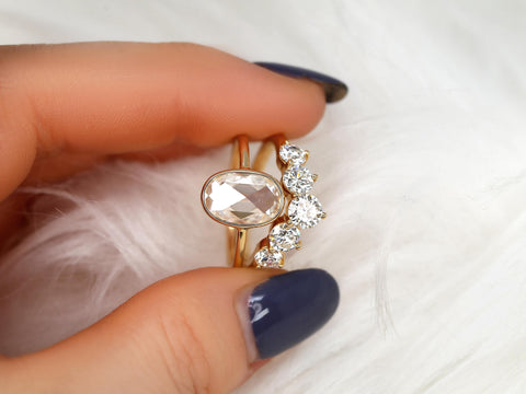 rose cut moissanite oval bezel ring with 5 stone wedding ring pinched between finger