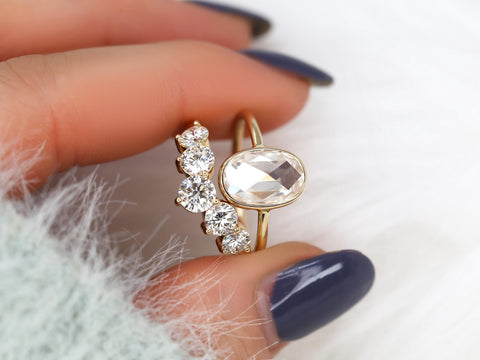 rose cut moissanite oval bezel ring with 5 stone wedding ring between 2 fingers