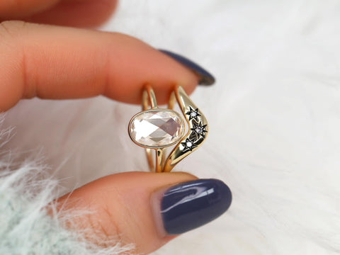 moissanite rose cut oval ring paired with a three diamond celestial curved band in gold on pinched finger