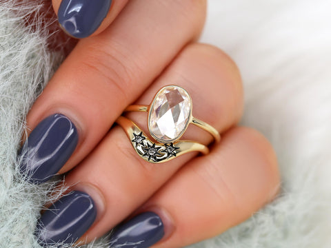 moissanite rose cut oval ring paired with a three diamond celestial curved band in gold on ring finger