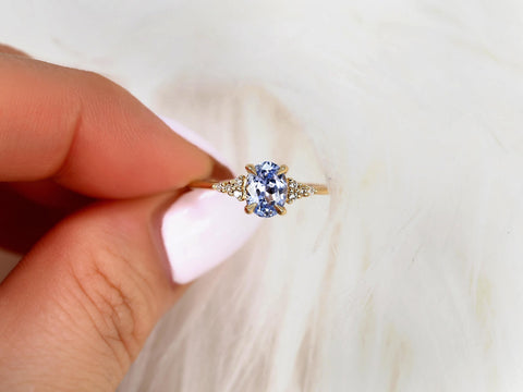 oval cornflower lilac sapphire cluster ring with dainty diamonds held between fingers top view