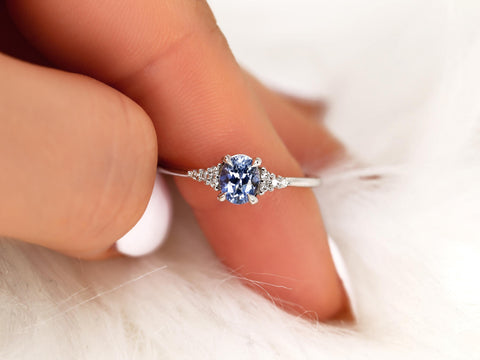 oval cluster ring with cornflower sapphire center stone over pointer facing down white background