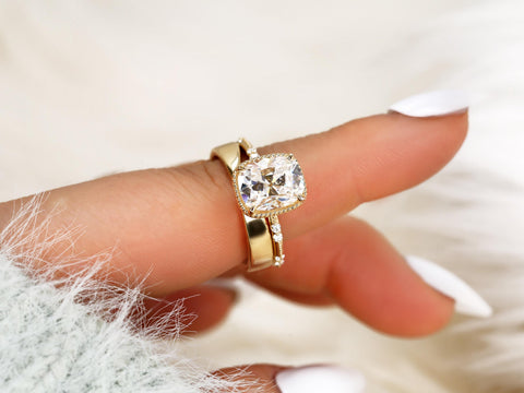 antique cushion solitaire with button back, claw prongs, and diamond accents on band. the ring is paired with a chevron solid gold band on pointer finger
