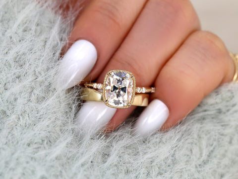 antique cushion solitaire with button back, claw prongs, and diamond accents on band. the ring is paired with a chevron solid gold band on ring finger