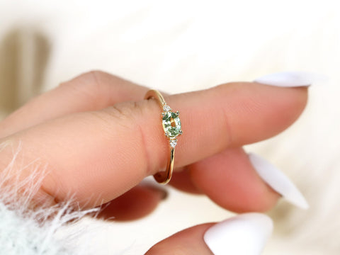 oval green sapphire ring in trilogy style with two diamonds on yellow gold on pointed finger