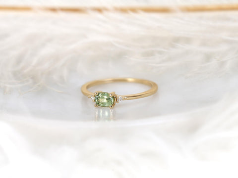 oval green sapphire ring in trilogy style with two diamonds on yellow gold on white background