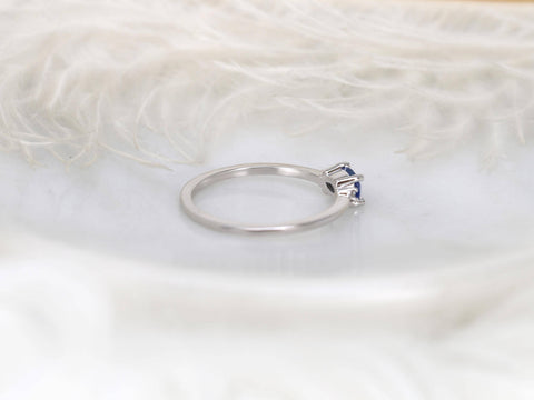 oval cornflower blue sapphire ring in trilogy style with two diamonds on white gold back view on white background with feathers