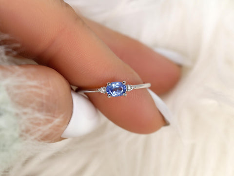 oval cornflower blue sapphire ring in three stone style with two diamonds on 14kt white gold on pointed finger